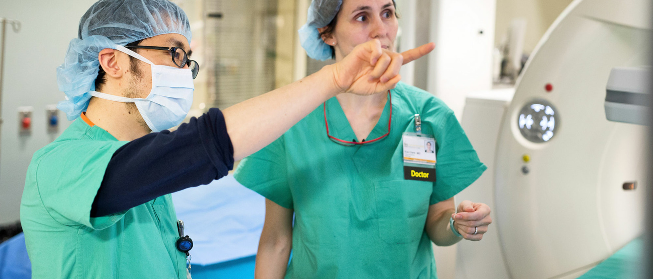 Two radiologists in interventional radiology suite discussing case